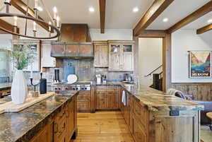 Kitchen featuring glass insert cabinets, brown cabinetry, tasteful backsplash, custom range hood, and a peninsula