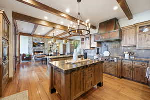 Kitchen with a kitchen island, beam ceiling, pendant lighting, a chandelier, and backsplash