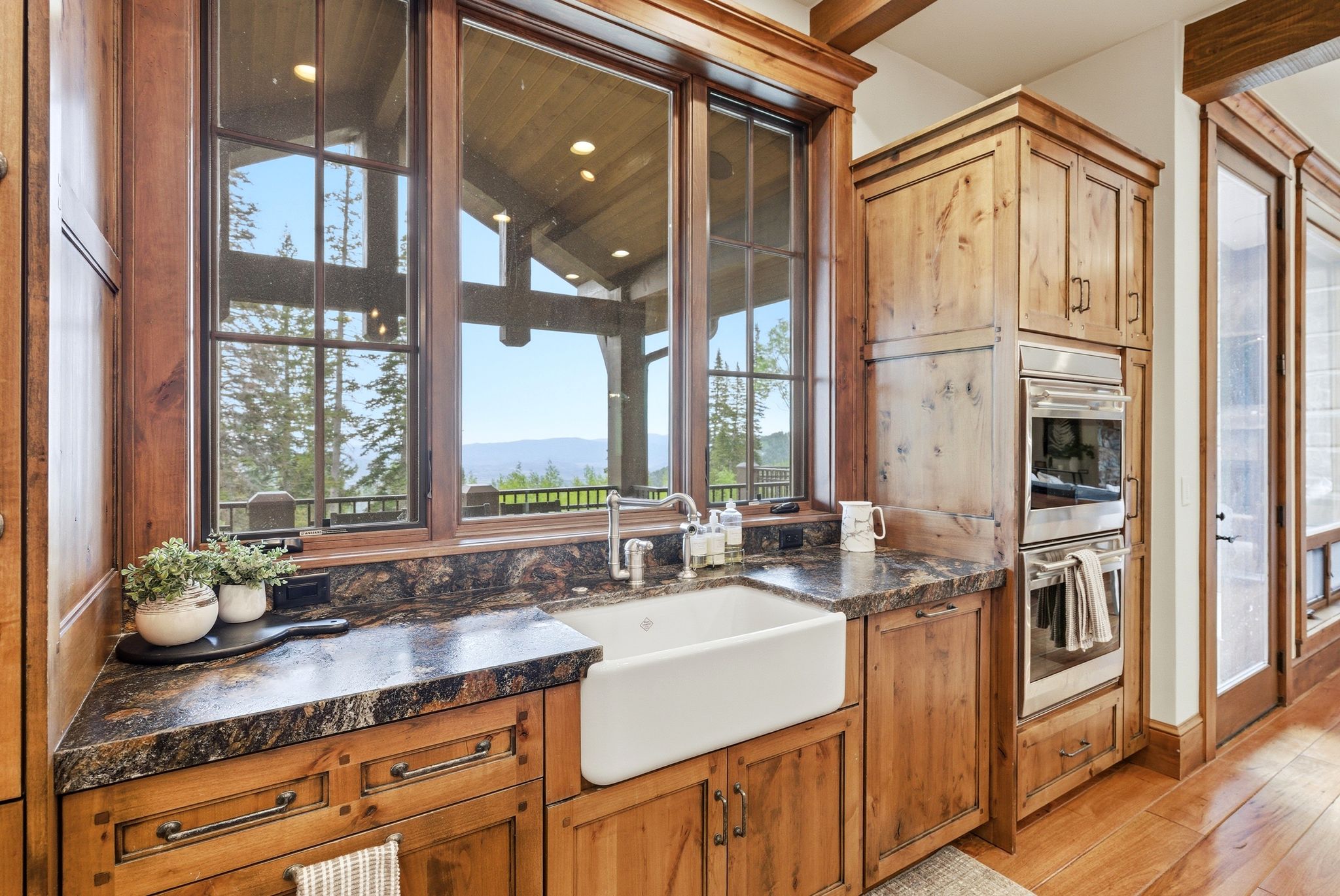 Kitchen workstation featuring a farmhouse sink, stone countertops, and wood-finish cabinetry