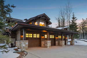 Property exterior at dusk with covered porch, stone siding, and a garage