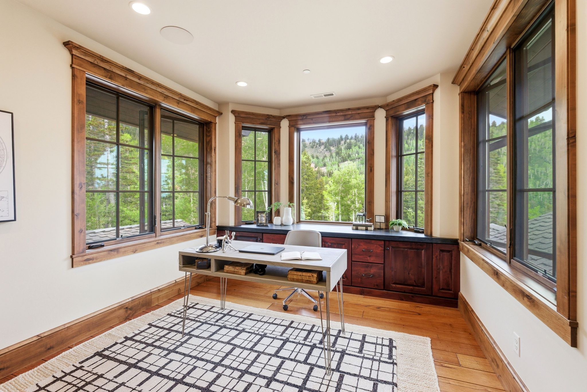 Room featuring multiple large windows with natural wood trim, built-in cabinetry with dark countertop, and recessed ceiling lighting