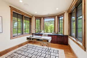 Room featuring multiple large windows with natural wood trim, built-in cabinetry with dark countertop, and recessed ceiling lighting