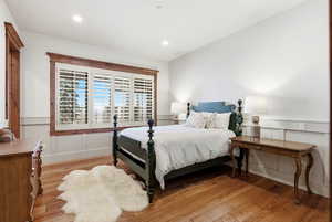 Bedroom with light wood-style flooring and a decorative wall