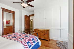 Bedroom with a decorative wall, light wood-style floors, crown molding, and a ceiling fan