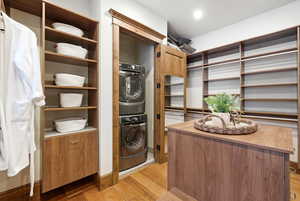 Laundry area featuring light wood-type flooring and stacked washer and clothes dryer