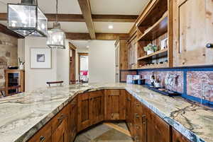 Kitchen featuring beamed ceiling, a kitchen breakfast bar, pendant lighting, coffered ceiling, and brown cabinets