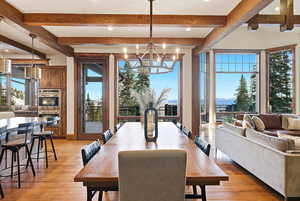 Dining area featuring a chandelier, light wood finished floors, recessed lighting, healthy amount of natural light, and beam ceiling