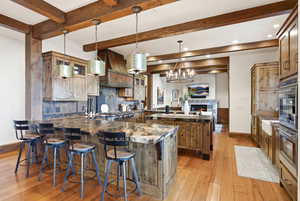Kitchen with glass insert cabinets, pendant lighting, a peninsula, decorative backsplash, and beam ceiling