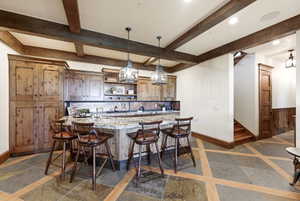 Custom kitchen island with stone countertop, accompanied by wooden cabinetry and exposed ceiling beams