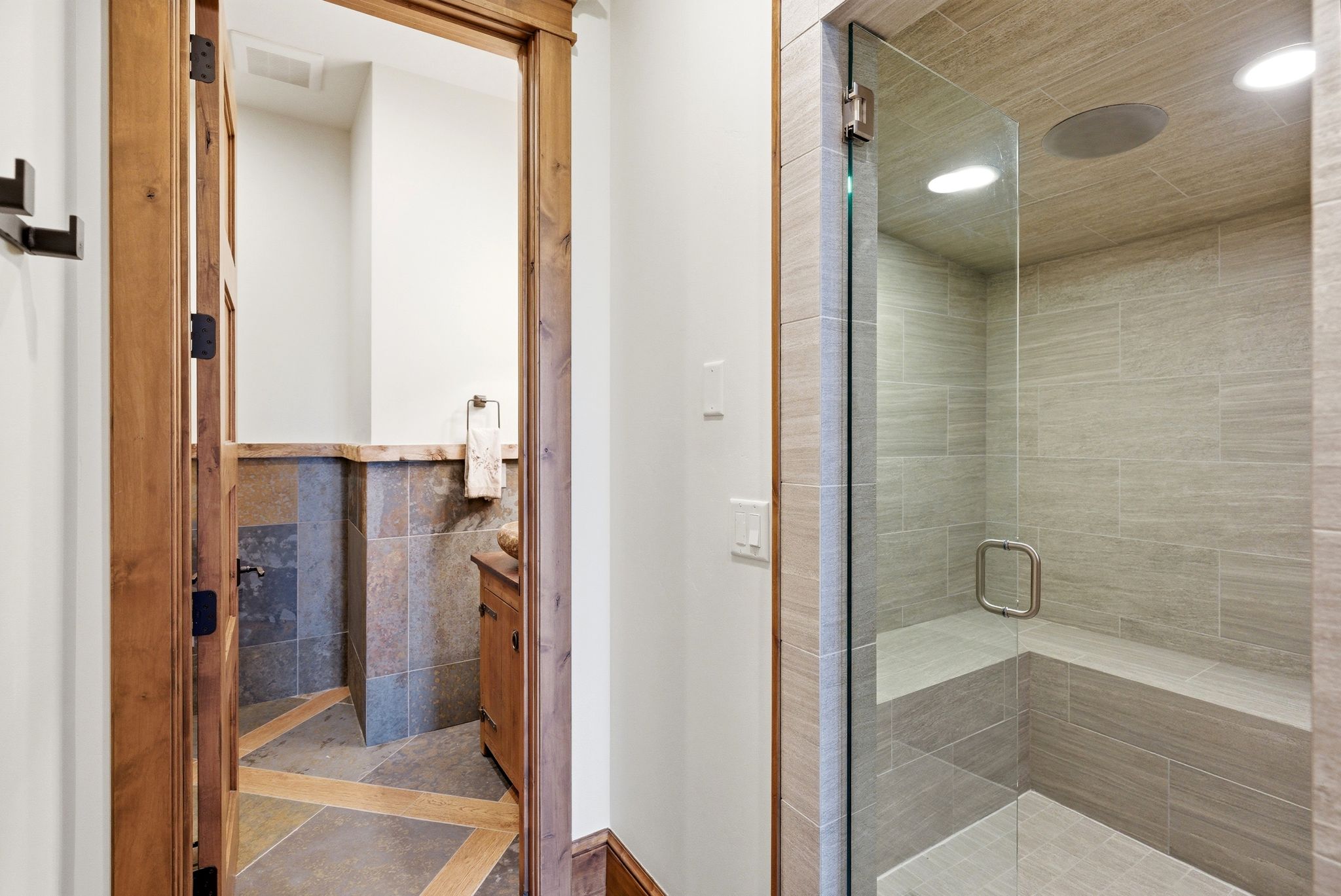 Glass-enclosed shower with a built-in bench, recessed lighting, and tile-finish walls