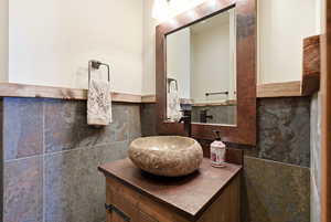 Bathroom with tile walls, vanity, and wainscoting