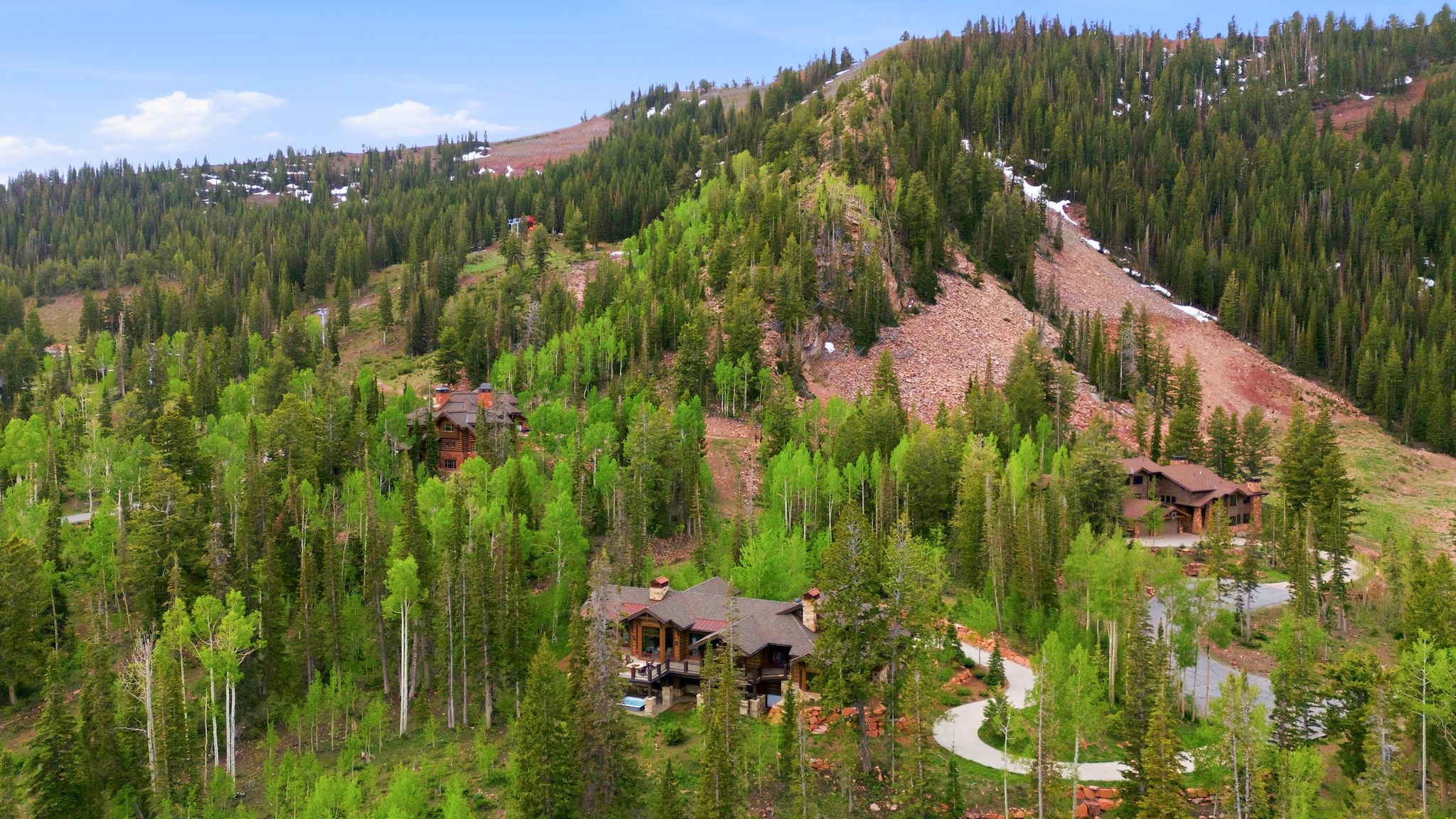 Mountain modern residence featuring multiple exterior balconies, a prominent stone chimney, and a dark shingled roof