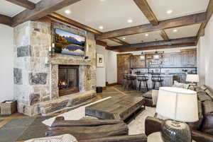 Living room with a fireplace, beam ceiling, beverage cooler, and recessed lighting