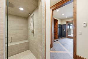 Walk-in shower with full tile surround, integrated bench, and rainfall showerhead with additional handheld spray