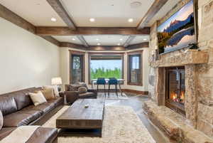 Stone-clad fireplace with a hearth, wood-beamed ceiling, recessed lighting, and bay windows