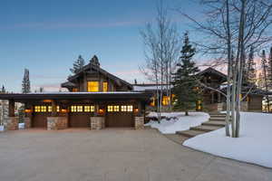 View of front of property featuring stone siding, driveway, and a garage