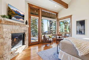 Bedroom featuring a glass covered fireplace, access to outside, hardwood / wood-style floors, multiple windows, and recessed lighting