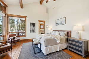 Bedroom with wood-type flooring, high vaulted ceiling, and beamed ceiling
