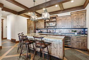 Kitchen featuring inlaid floor details, recessed lighting, pendant lighting, a breakfast bar, and decorative backsplash