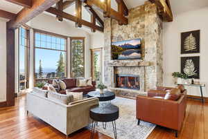Living room with high vaulted ceiling, hardwood / wood-style flooring, a fireplace, and beamed ceiling