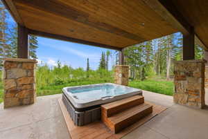 Covered patio featuring an integrated hot tub with wood-finish steps