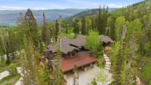 Mountain property featuring a multi-level design with a prominent copper-toned metal roof section, a stone and wood exterior, and a shingle roof