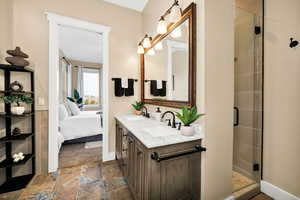 Full bath featuring ensuite bath, double vanity, a stall shower, and stone tile flooring