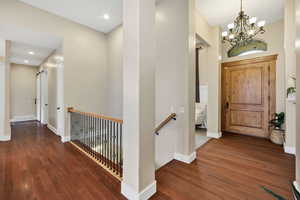 Entryway with dark wood-style flooring and a chandelier
