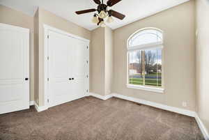 Unfurnished bedroom featuring carpet flooring, a closet, and a ceiling fan