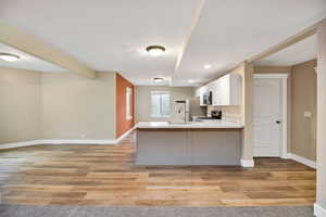 Kitchen with light countertops, stainless steel appliances, white cabinetry, open floor plan, and a peninsula