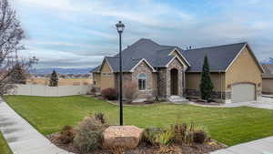 View of front facade with stone siding, stucco siding, and driveway