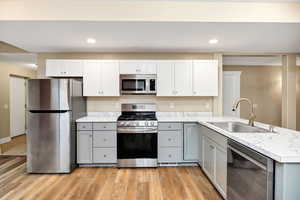 Kitchen featuring stainless steel appliances, gray cabinets, light countertops, recessed lighting, and white cabinets