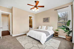 Bedroom with light carpet, ceiling fan, and ensuite bathroom
