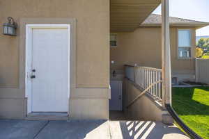 Entrance to property with stucco siding and roof with shingles