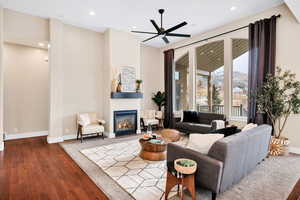 Living room with a glass covered fireplace, wood-type flooring, recessed lighting, and ceiling fan