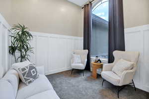Sitting room with a decorative wall, wainscoting, and carpet floors