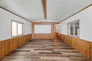 Unfurnished room with ornamental molding, wooden walls, wainscoting, and wood finished floors