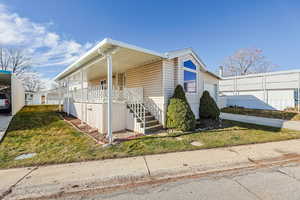 Manufactured / mobile home with a front yard, concrete driveway, and covered porch