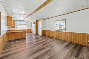 Kitchen with wood walls, plenty of natural light, a peninsula, a wainscoted wall, and brown cabinetry