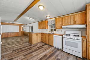 Kitchen with white appliances, wood walls, dark wood finished floors, light countertops, and wainscoting