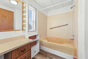 Full bath with tub / shower combination, dark wood-style flooring, and vanity