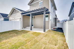 Rear view of property featuring board and batten siding, a pergola, a fenced backyard, and a patio