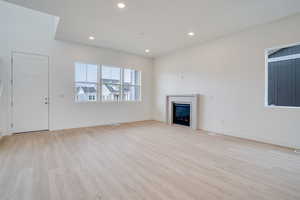 Unfurnished living room featuring light wood finished floors, recessed lighting, and a fireplace