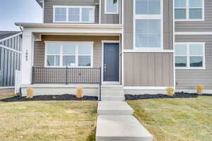 Entrance to property with board and batten siding, a yard, and covered porch