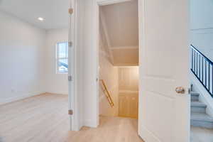 Stairs featuring wood finished floors and recessed lighting