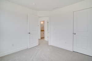 Unfurnished bedroom featuring light colored carpet and baseboards