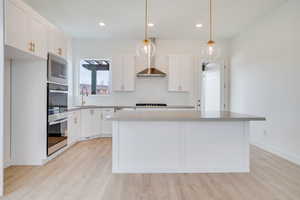 Kitchen featuring white cabinetry, pendant lighting, stainless steel appliances, backsplash, and recessed lighting