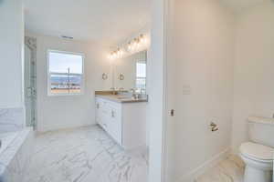 Full bathroom with light marble finish floors, double vanity, a marble finish shower, and a tub to relax in