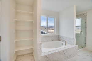 Bathroom featuring light marble finish flooring, a bath, and a marble finish shower