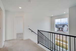 Corridor featuring an upstairs landing, light colored carpet, and recessed lighting